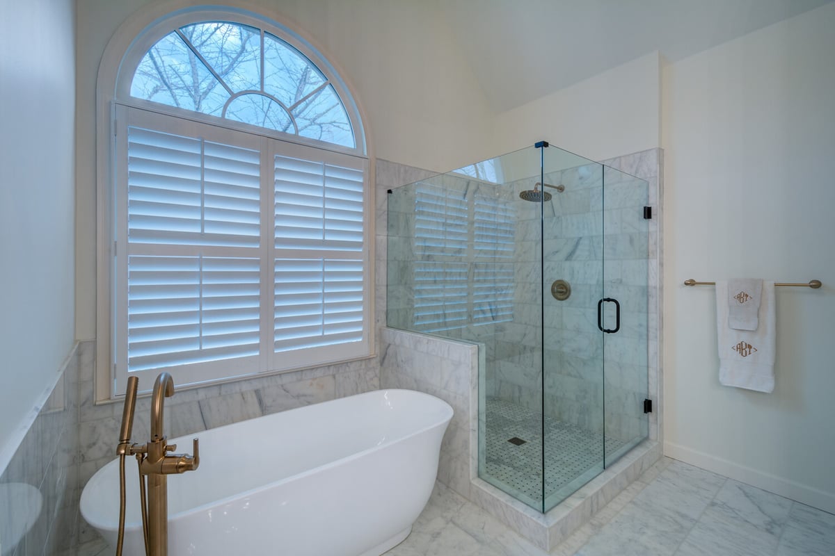 Spacious marble bathroom remodel with arched window and walk-in shower by Silver Oak Remodel in Atlanta, GA