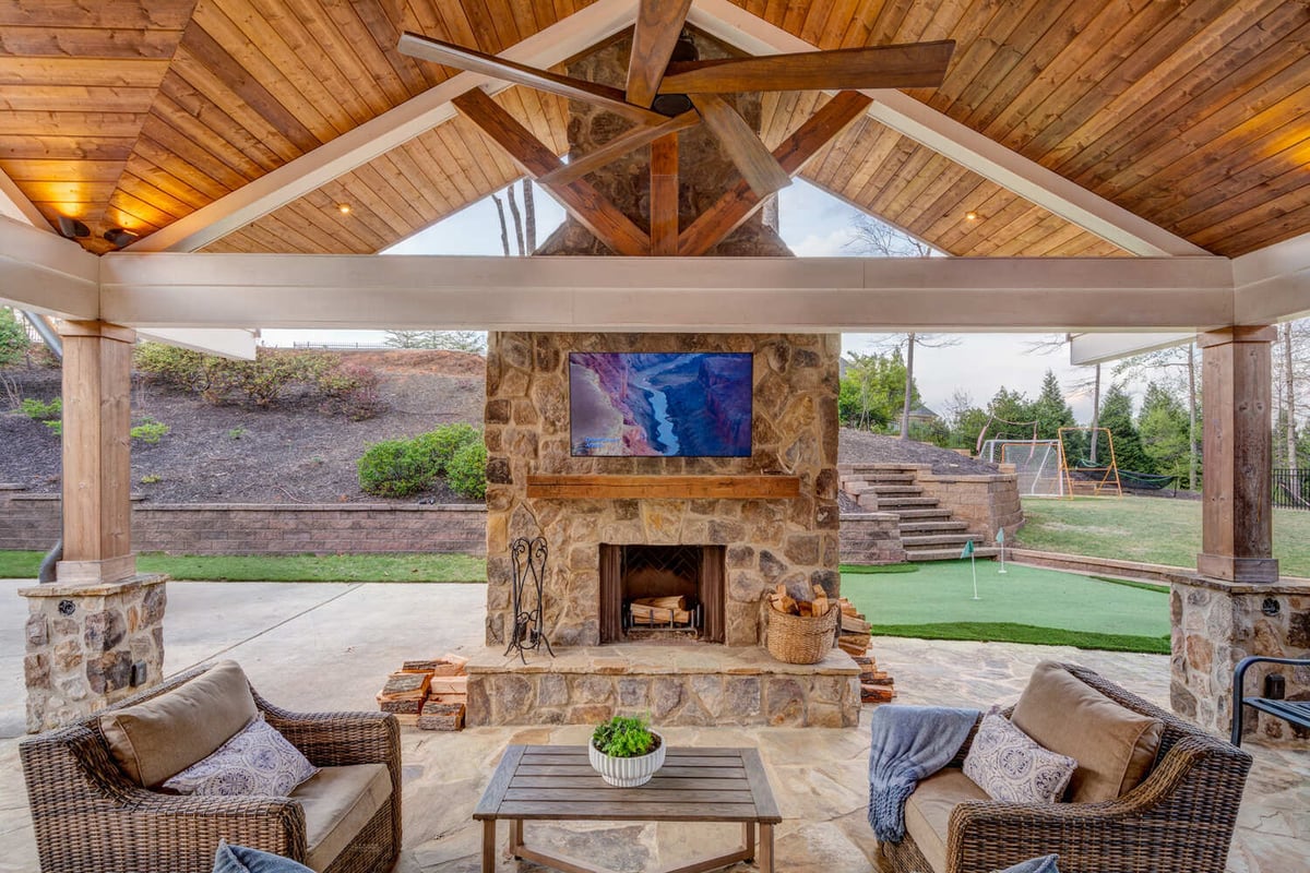 Stone fireplace under vaulted ceiling in covered patio area remodeled by Silver Oak in Roswell, GA