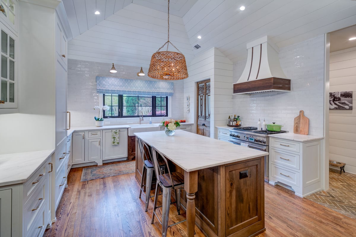 Wide view of kitchen with marble island and custom range hood by Silver Oak in Roswell, GA