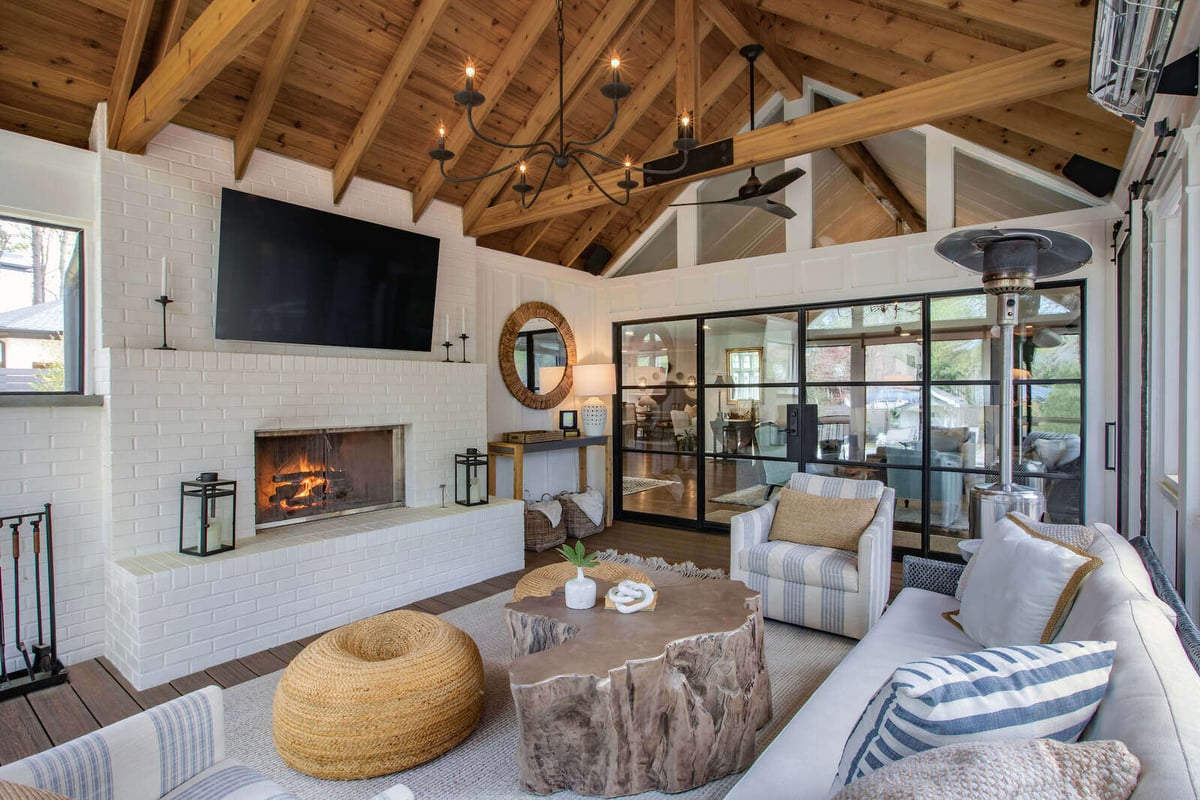 East Cobb GA porch addition by Silver Oak Remodel showcasing brick fireplace, TV, and rustic coffee table