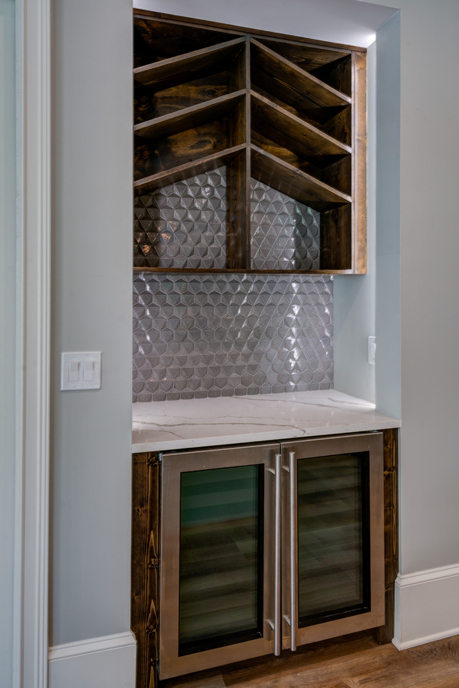 Custom wine nook with geometric tile and wood shelving in Greater Atlanta basement by Silver Oak Remodel
