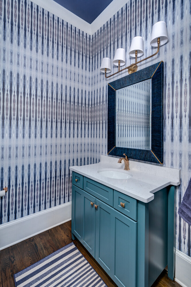 Powder room remodel with teal vanity and bold patterned wallpaper by Silver Oak Remodel in Greater Atlanta