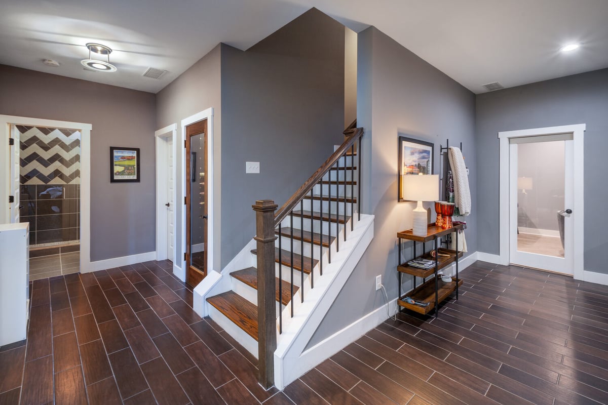Basement hallway with stylish tile flooring and open stairway by Silver Oak Remodel in Greater Atlanta