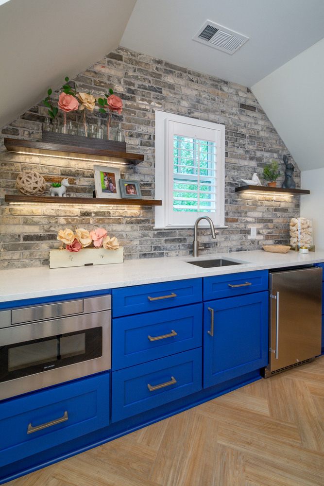 Bold kitchen design with cobalt blue cabinetry and exposed brick wall by Silver Oak Remodel in Greater Atlanta