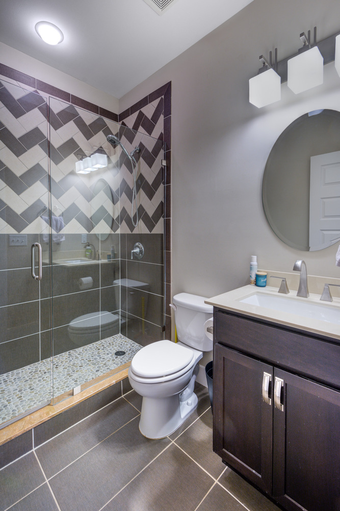 Guest bathroom with bold chevron tile shower and modern vanity by Silver Oak Remodel in Greater Atlanta