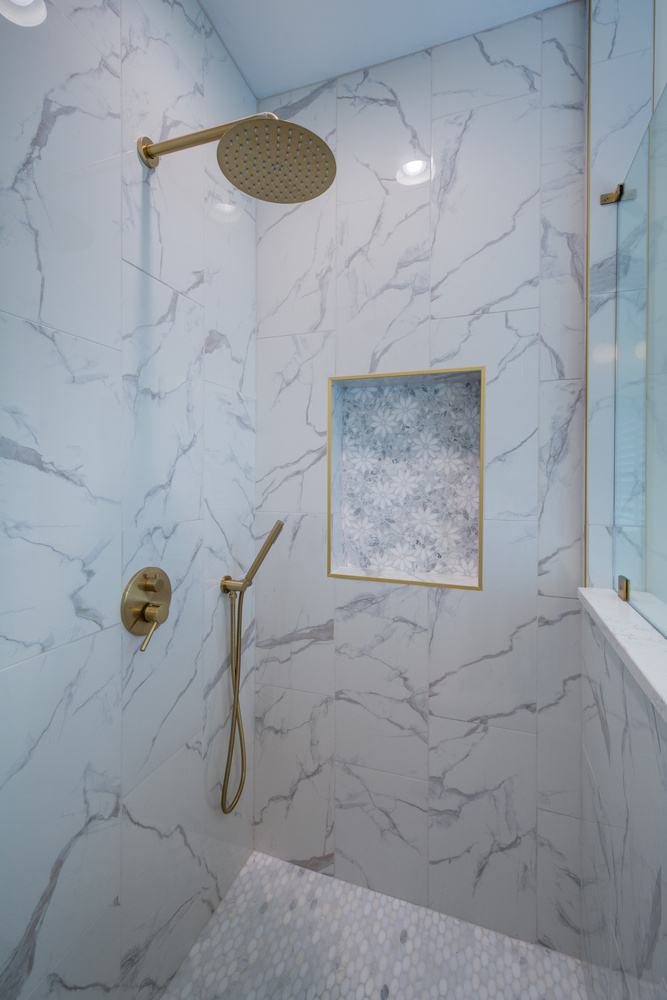 Luxurious walk-in shower with gold hardware and marble tile by Silver Oak Remodel in Greater Atlanta